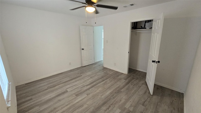 unfurnished bedroom with ceiling fan, wood finished floors, visible vents, baseboards, and a closet