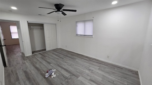 unfurnished bedroom with baseboards, a closet, visible vents, and wood finished floors