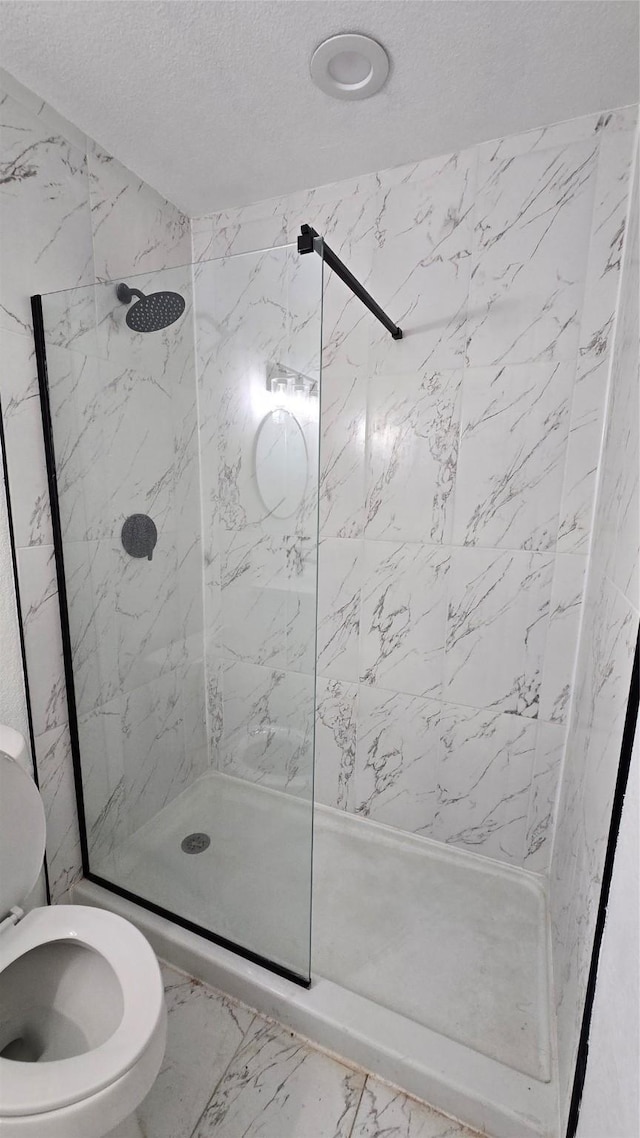 full bath with toilet, marble finish floor, a shower stall, and a textured ceiling