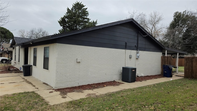 view of property exterior featuring a yard, central AC unit, fence, and brick siding