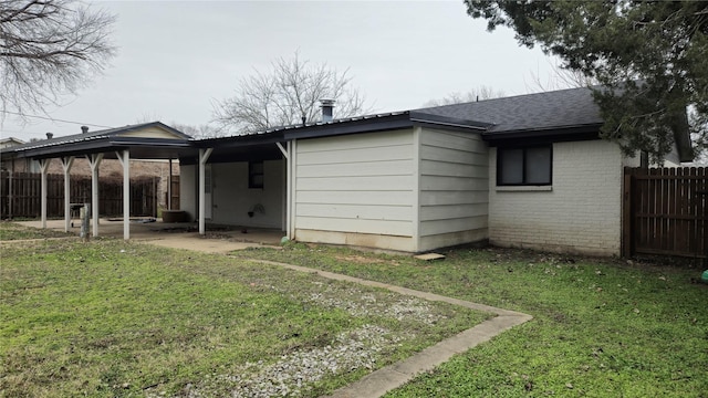 rear view of house featuring a patio, roof with shingles, fence, a yard, and brick siding