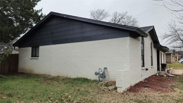 view of side of property featuring brick siding and fence