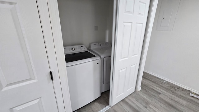 laundry room with baseboards, electric panel, washer and clothes dryer, and light wood finished floors