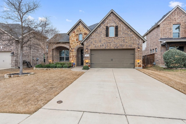 view of front of property featuring stone siding, brick siding, an attached garage, and driveway