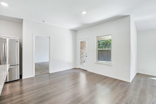 unfurnished living room featuring dark wood-style flooring and baseboards