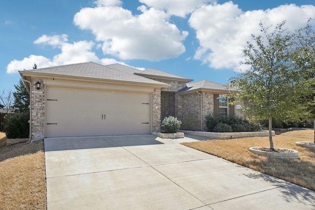 prairie-style house featuring a garage, concrete driveway, and brick siding