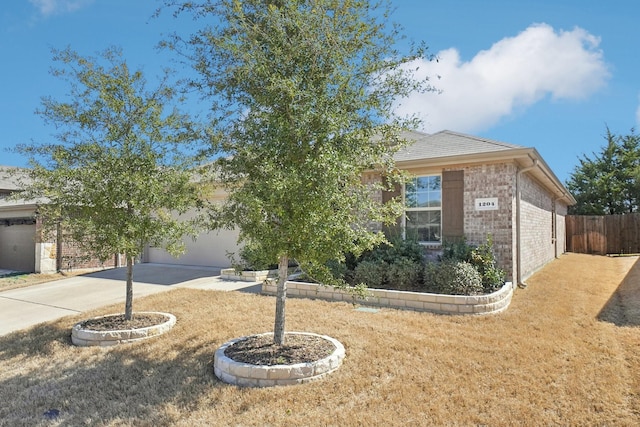 view of front of property with an attached garage, fence, concrete driveway, and brick siding