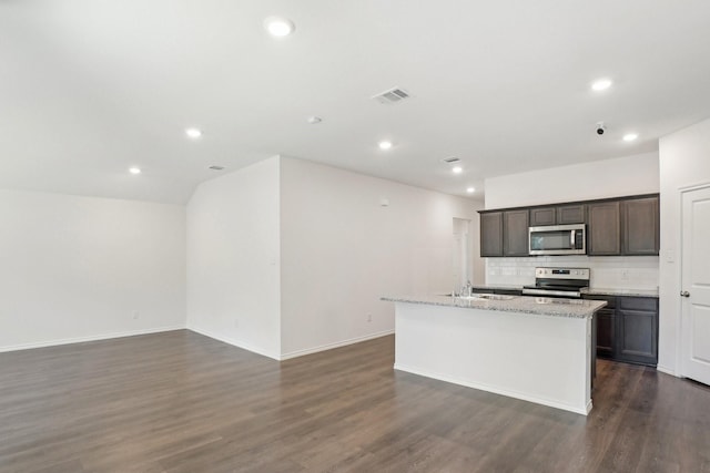 kitchen featuring a kitchen island with sink, stainless steel appliances, dark wood-type flooring, a sink, and backsplash