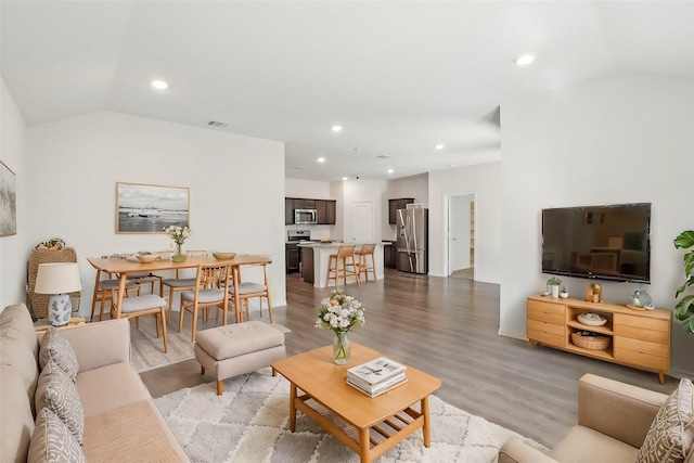 living area with light wood-type flooring, vaulted ceiling, and recessed lighting