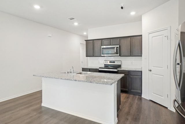 kitchen with tasteful backsplash, a center island with sink, visible vents, appliances with stainless steel finishes, and a sink