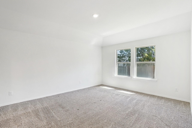 carpeted spare room with baseboards and vaulted ceiling