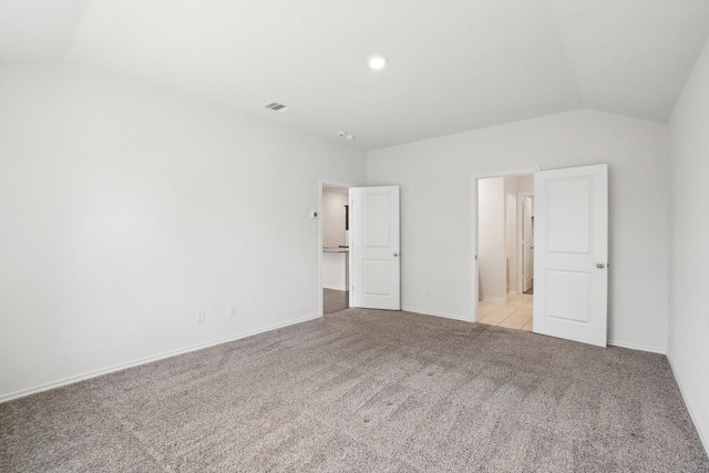 unfurnished bedroom featuring lofted ceiling, light colored carpet, visible vents, and baseboards