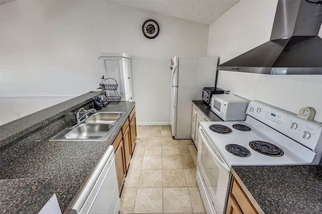 kitchen with white appliances, dark countertops, wall chimney exhaust hood, brown cabinets, and a sink