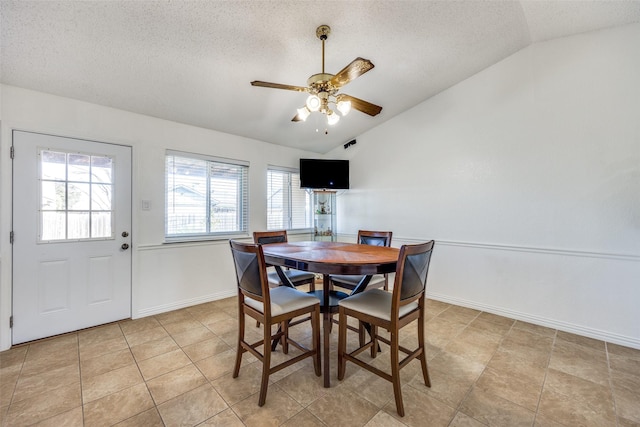 dining area featuring vaulted ceiling, ceiling fan, a textured ceiling, and baseboards