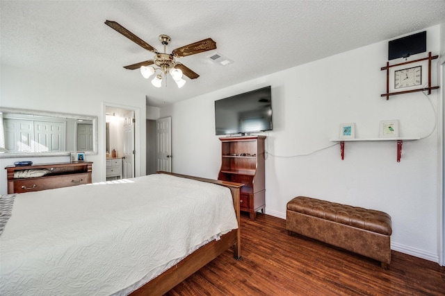 bedroom featuring visible vents, a textured ceiling, baseboards, and wood finished floors