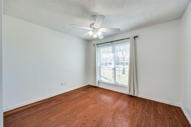 empty room featuring a textured ceiling, baseboards, and wood finished floors