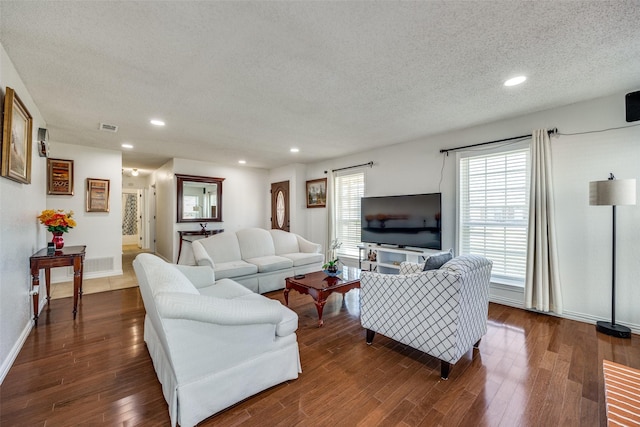 living room featuring a textured ceiling, recessed lighting, dark wood-style flooring, visible vents, and baseboards