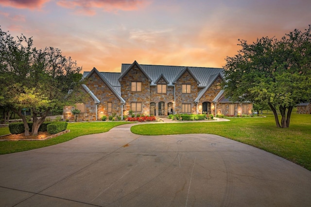 view of front of house featuring a front yard, concrete driveway, metal roof, and a standing seam roof