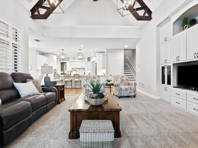 living room featuring light colored carpet, visible vents, an inviting chandelier, high vaulted ceiling, and baseboards