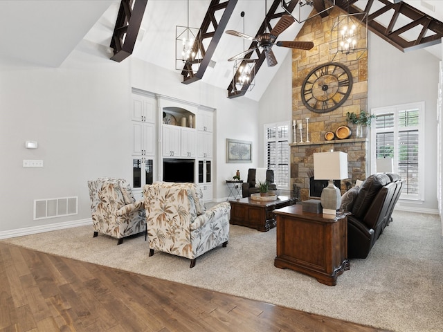 living area with a fireplace, visible vents, wood finished floors, high vaulted ceiling, and ceiling fan with notable chandelier