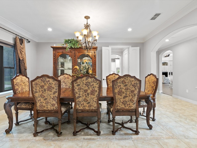 dining room featuring baseboards, arched walkways, a chandelier, and ornamental molding