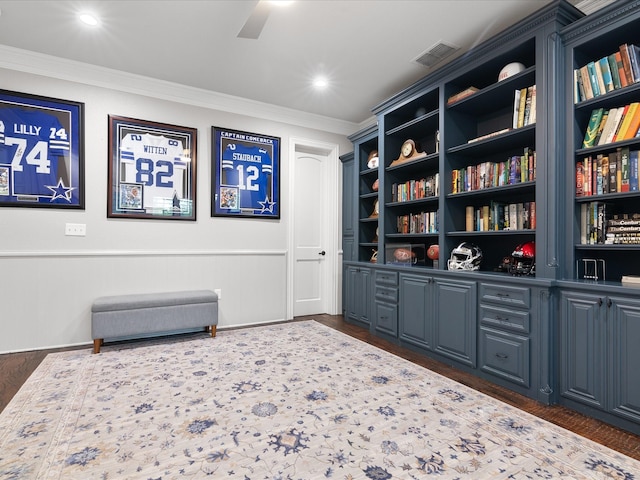 sitting room featuring a wainscoted wall, visible vents, a ceiling fan, and ornamental molding