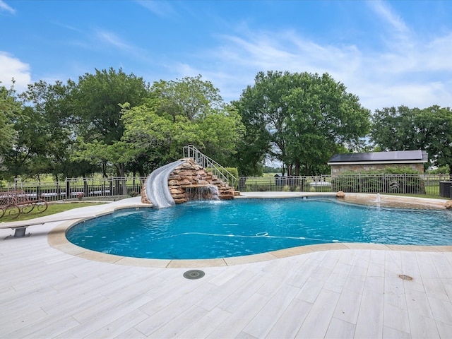 view of pool featuring a fenced in pool, a water slide, fence, and stairway