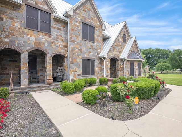 view of front of home featuring metal roof, a standing seam roof, and stone siding