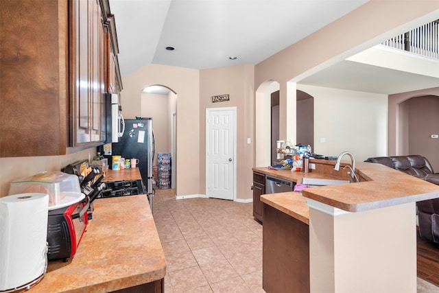 kitchen with arched walkways, light tile patterned floors, light countertops, white microwave, and a sink