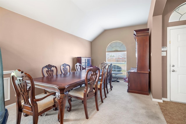 dining room featuring light carpet, baseboards, and vaulted ceiling