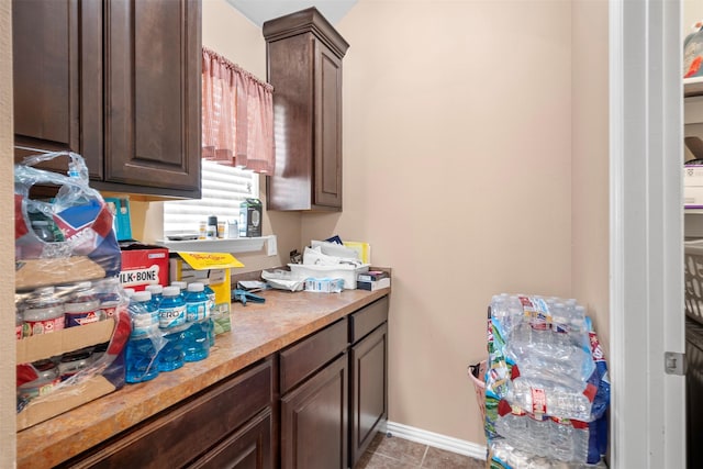 clothes washing area featuring light tile patterned floors and baseboards