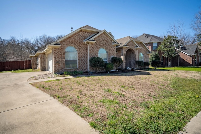 view of front facade featuring brick siding, an attached garage, fence, driveway, and a front lawn