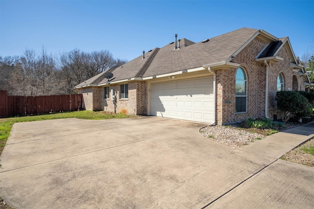 view of front of property with driveway, brick siding, an attached garage, and fence