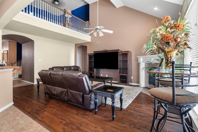 living area featuring high vaulted ceiling, arched walkways, and wood finished floors