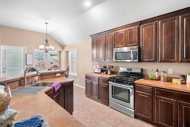 kitchen with lofted ceiling, light countertops, appliances with stainless steel finishes, dark brown cabinets, and pendant lighting