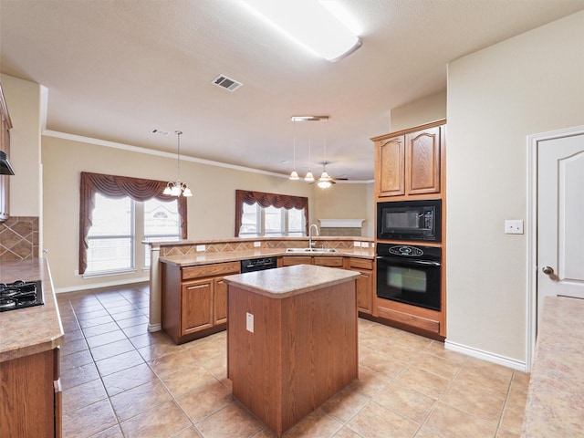 kitchen featuring a sink, visible vents, light countertops, a center island, and black appliances