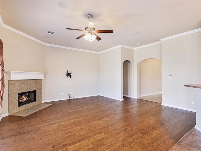 unfurnished living room with visible vents, arched walkways, a tile fireplace, ceiling fan, and wood finished floors