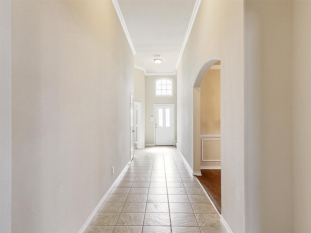 doorway with ornamental molding, arched walkways, and baseboards