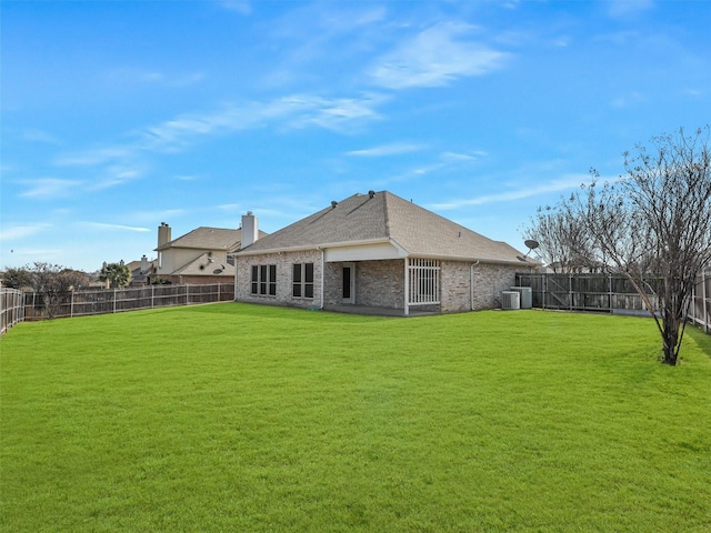 rear view of house with brick siding, a lawn, cooling unit, and a fenced backyard