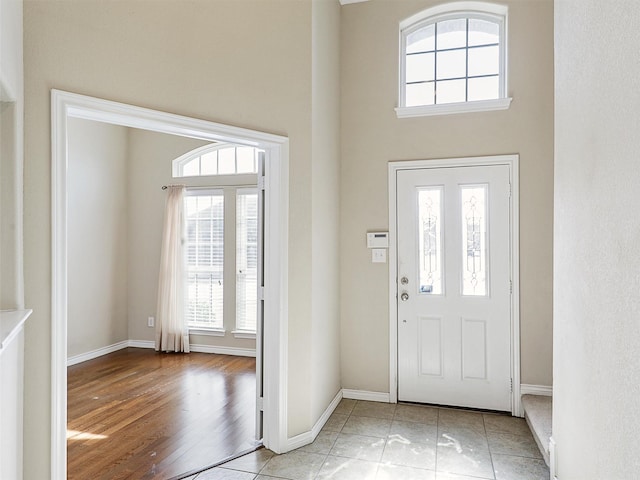 foyer with baseboards, a high ceiling, and light wood-style floors