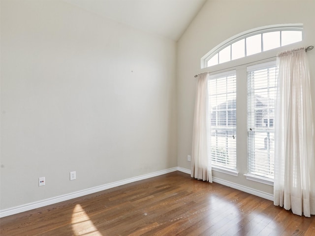 spare room featuring lofted ceiling, wood finished floors, and baseboards