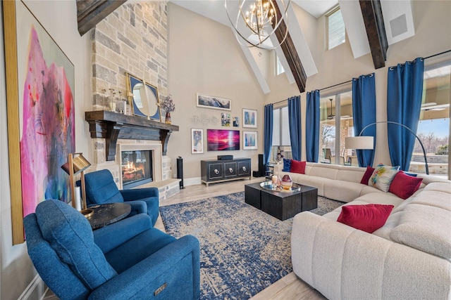 living room with high vaulted ceiling, a notable chandelier, a fireplace, wood finished floors, and baseboards