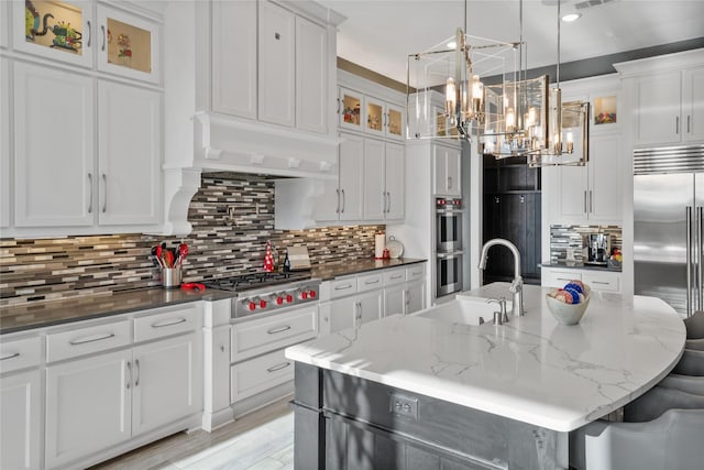 kitchen featuring appliances with stainless steel finishes, white cabinets, a sink, and custom exhaust hood