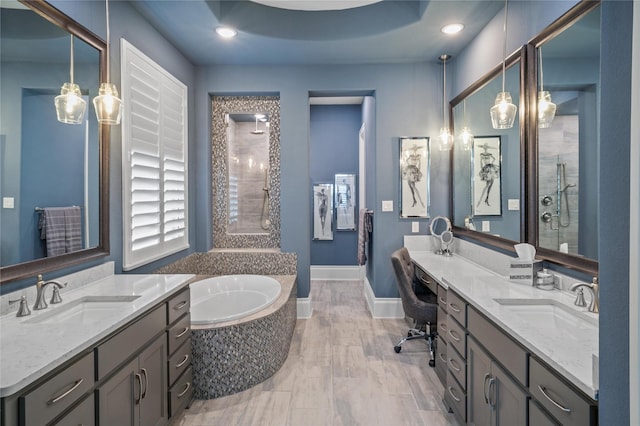 bathroom featuring a bath, a shower stall, baseboards, and a sink