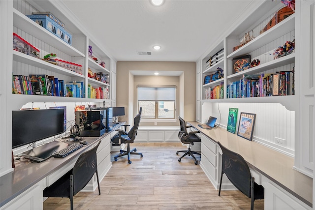 office with light wood-style floors, visible vents, and built in study area