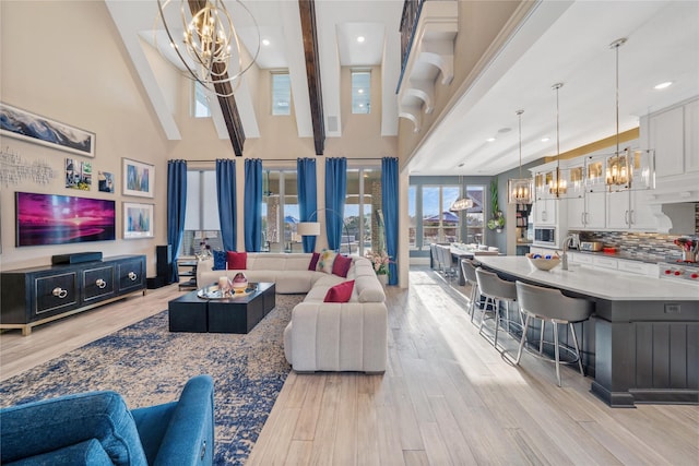 living area with light wood-style flooring, a high ceiling, a notable chandelier, and recessed lighting