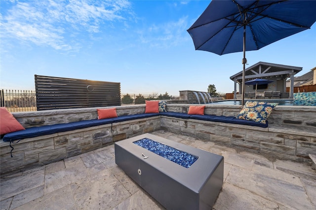 view of patio with fence, a fire pit, and a gazebo