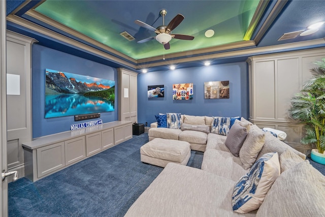 home theater room featuring a ceiling fan, a tray ceiling, visible vents, and carpet flooring