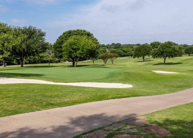 view of home's community with view of golf course and a yard