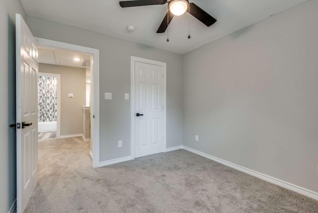 unfurnished bedroom featuring attic access, carpet, ceiling fan, and baseboards